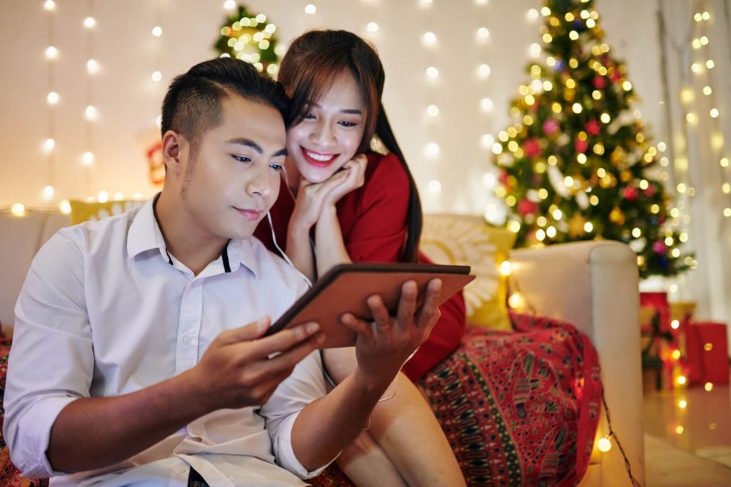 happy couple looking at christmas deals online