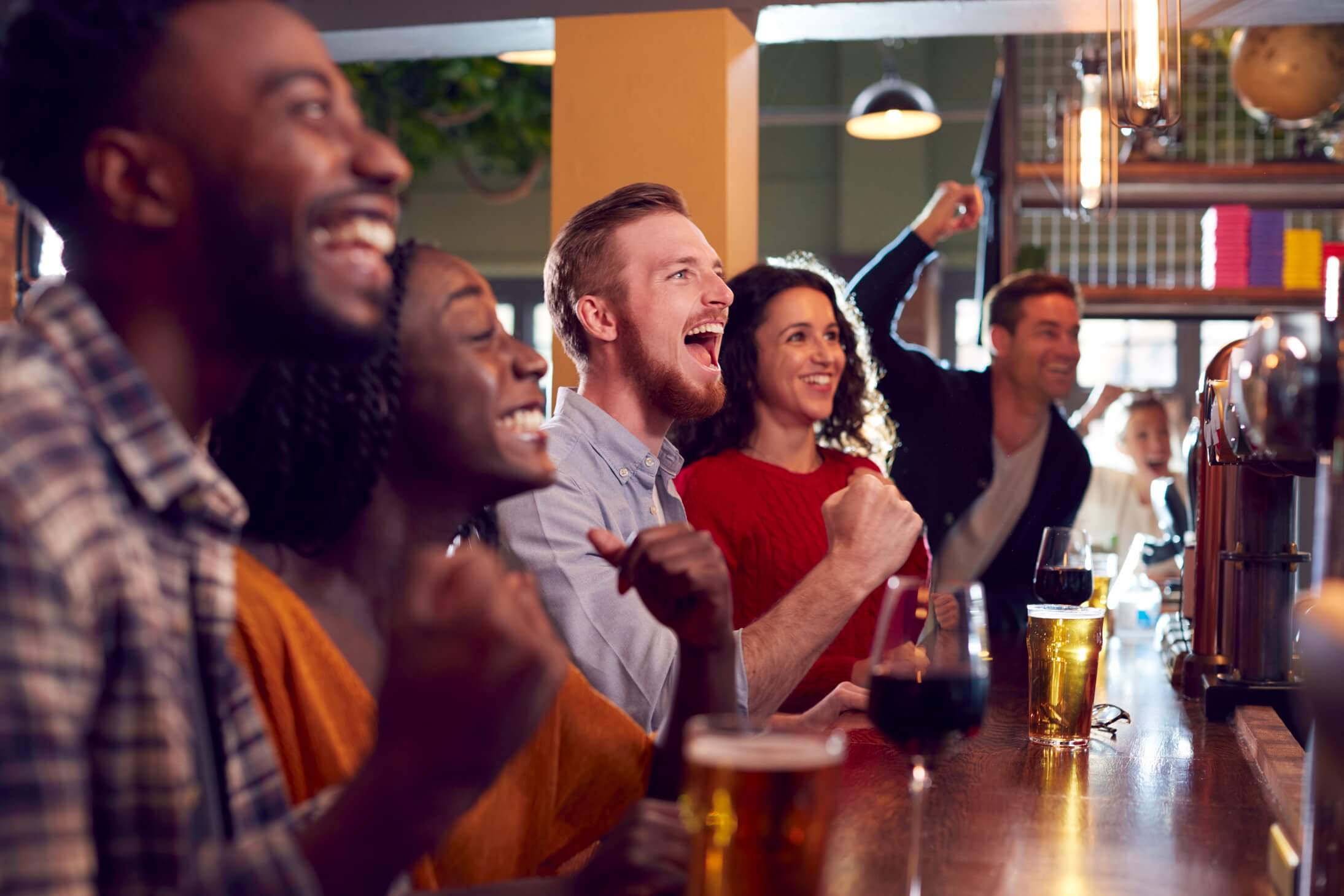 group of excited customers in sports bar watching