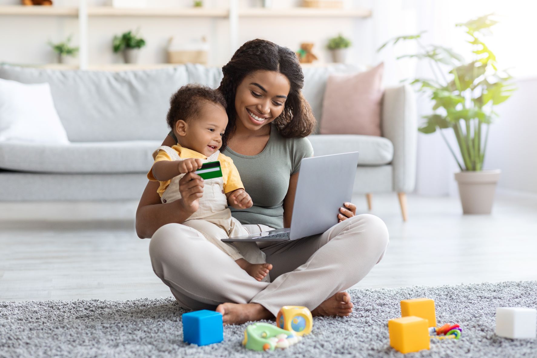 black mother with infant baby using laptop
