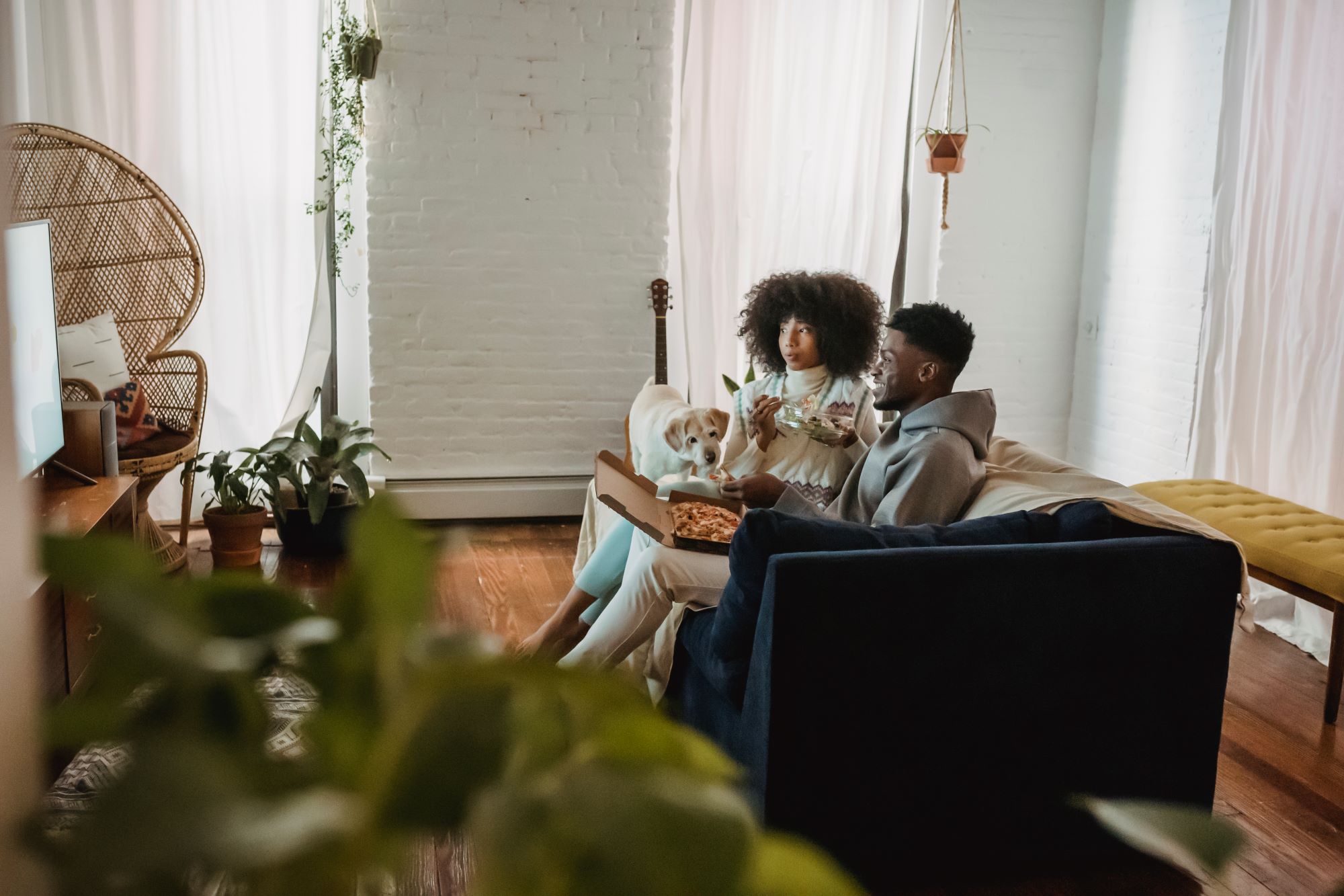 couple watching tv eating on sofa