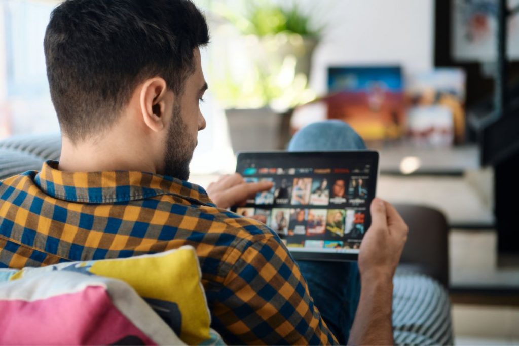 man choosing movie for streaming on tablet